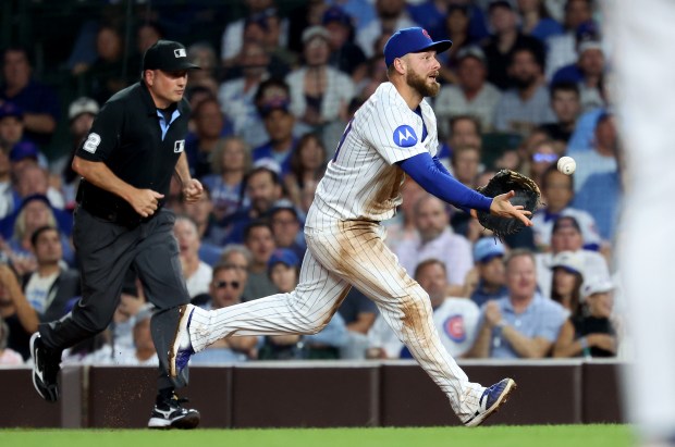 Chicago Cubs first baseman Michael Busch tosses the ball to starting pitcher Jameson Taillon in an attempt to get an out at first base in the second inning of Game 2 of a doubleheader against the Milwaukee Brewers at Wrigley Field in Chicago on Aug. 19, 2025. (Chris Sweda/Chicago Tribune)