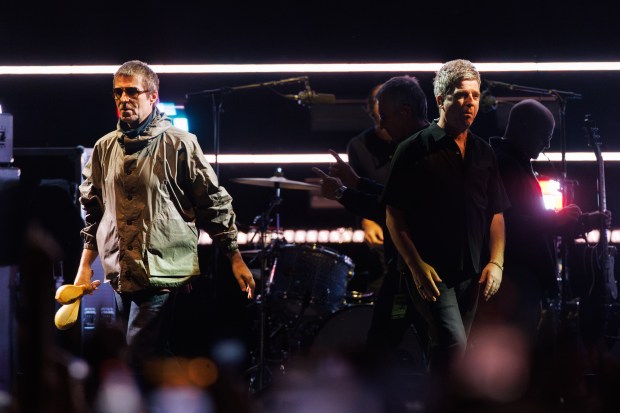From left, Liam Gallagher and his brother Noel Gallagher walk...