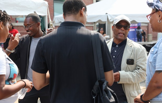 Walter Redmond Burnett, left, and his father, Ald. Walter Burnett Jr., 27th, right, talk with colleagues during the "Oh! Snap! Youth Block Party" on July 31, 2025, in Chicago. (John J. Kim/Chicago Tribune)