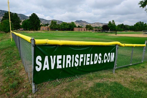 A sign for saveirisfields.com is seen on the fence in an outfield at Iris Fields in Boulder on Monday. Boulder County has listed the North Broadway Complex for sale, including the baseball fields. (Matthew Jonas/Staff Photographer)