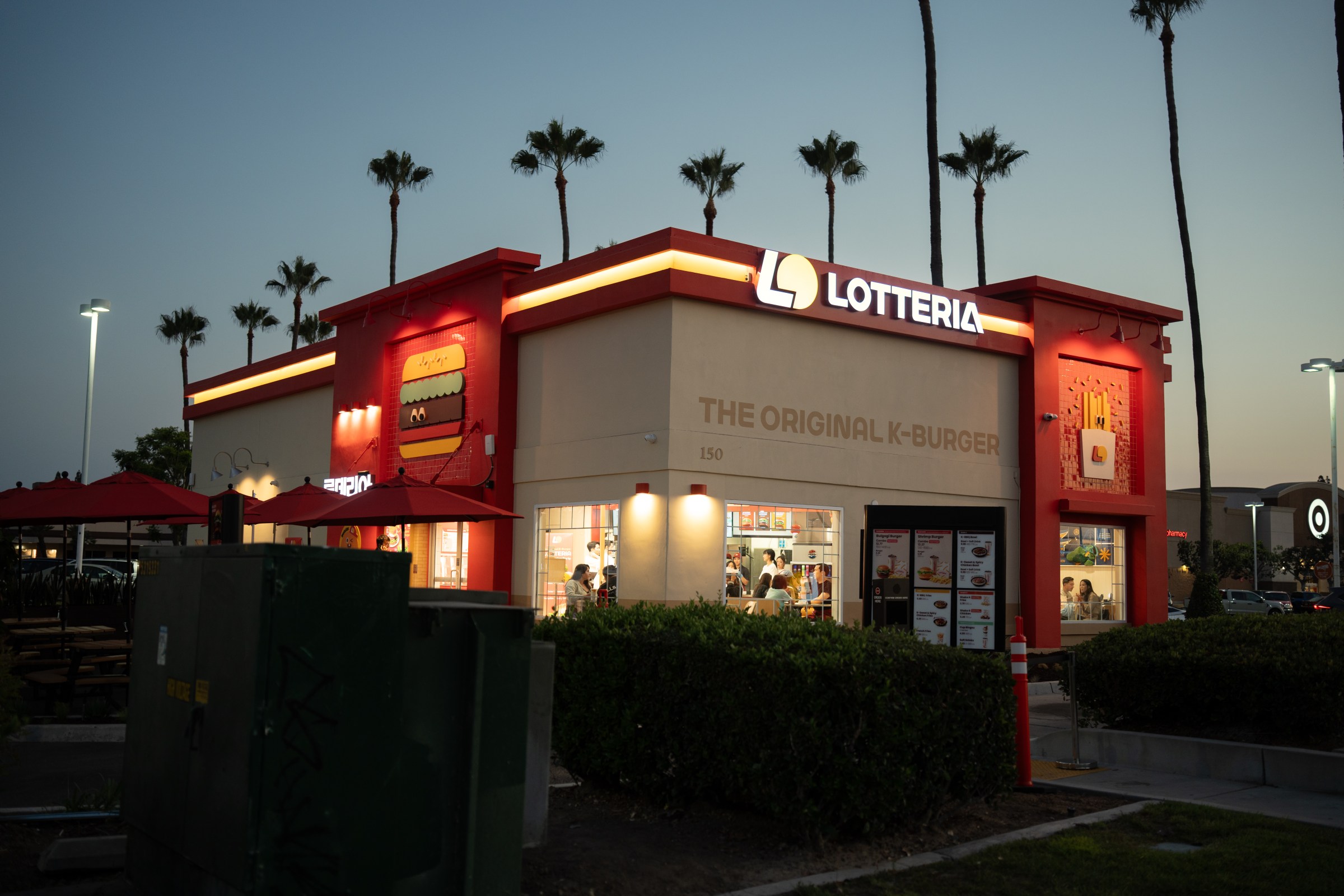Exterior of Lotteria in Fullerton in the evening, with lights along the side and palm trees in the background