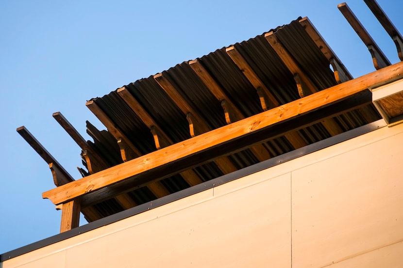 A section of corrugated metal roof is seen damaged on the roof-top pergola of a 5-story,...