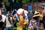 Performers with Alma Oaxaqueña toss fruit to La Guelaguetza attendees in Shute Park in Hillsboro, Ore., on Aug. 9, 2025.