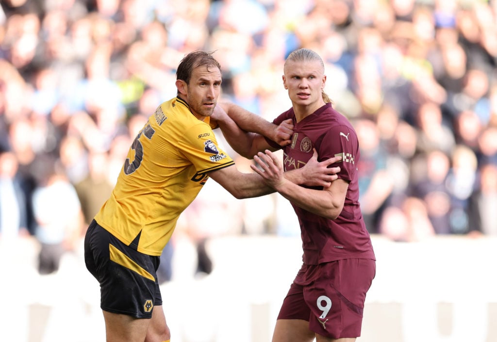 Manchester City striker Erling Haaland battles with Wolves defender Craig Dawson.