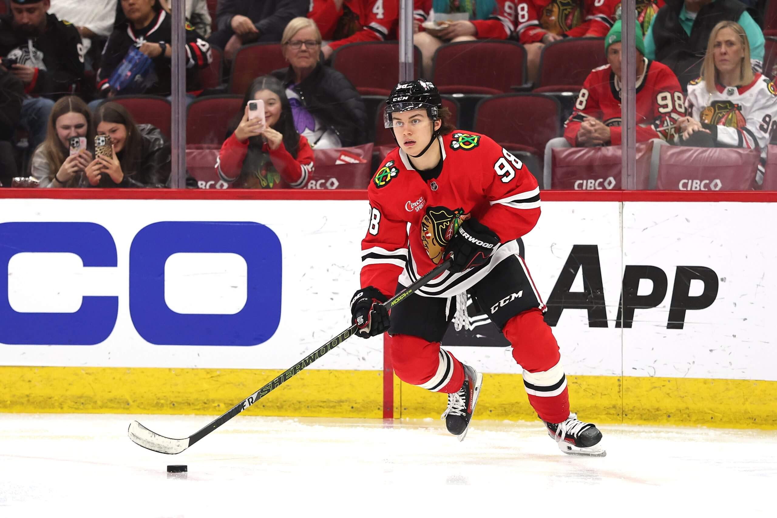 Connor Bedard skates with the puck in his red No. 98 Chicago jersey.
