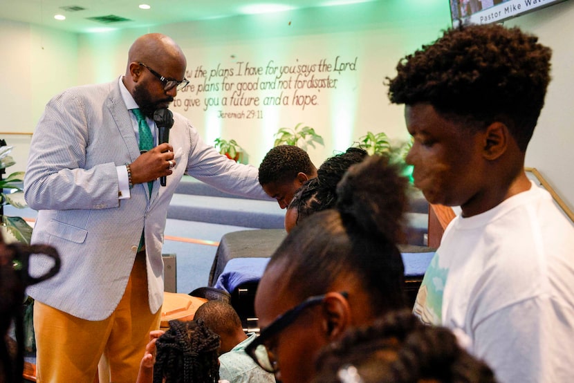 Rev. Michael Waters prays with youth ahead of the start of the school year during a...