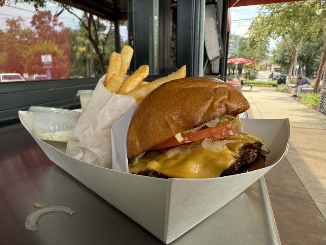 A burger and fries sits on a stand table at Boo's Burger.