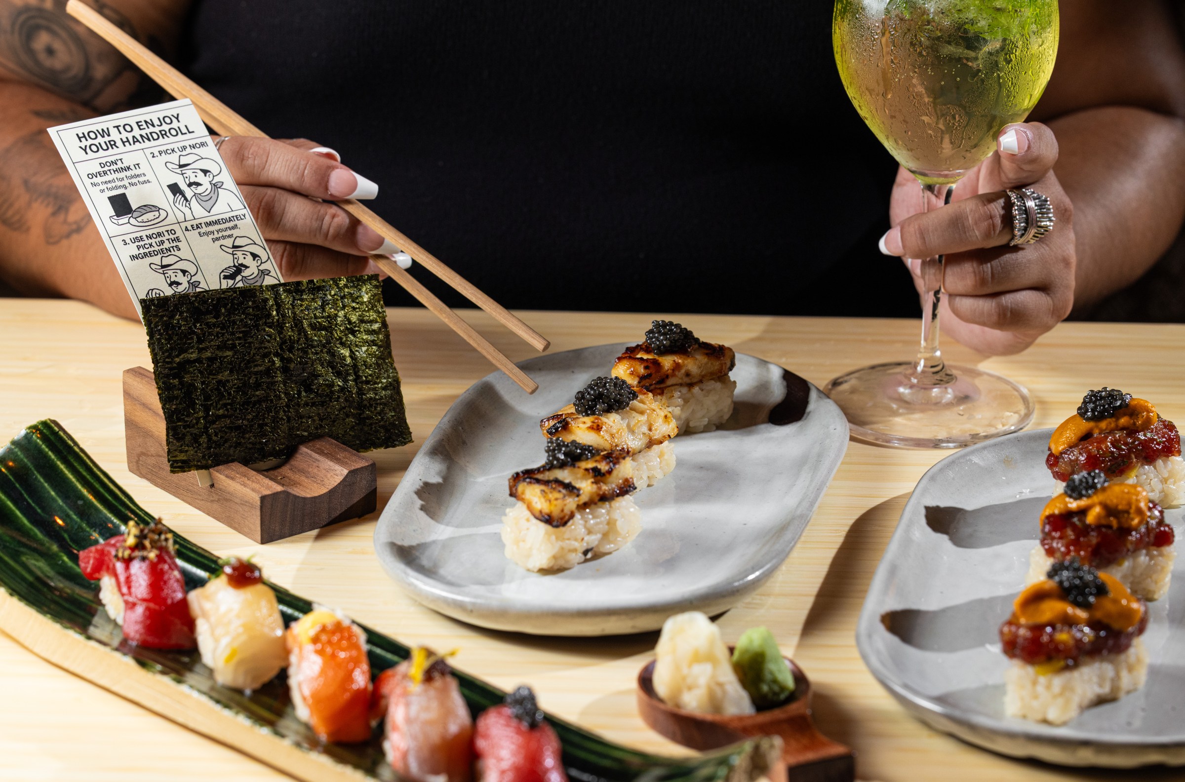 Handrolls and nigiri sit on a table in front of a diner.