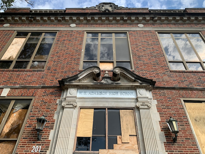 The front of old W.H. Adamson High School, which appears to have far more boarded-up windows...