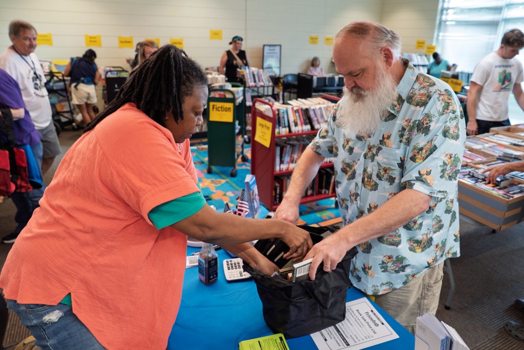 A woman puts books in a bag for a man at the book sale