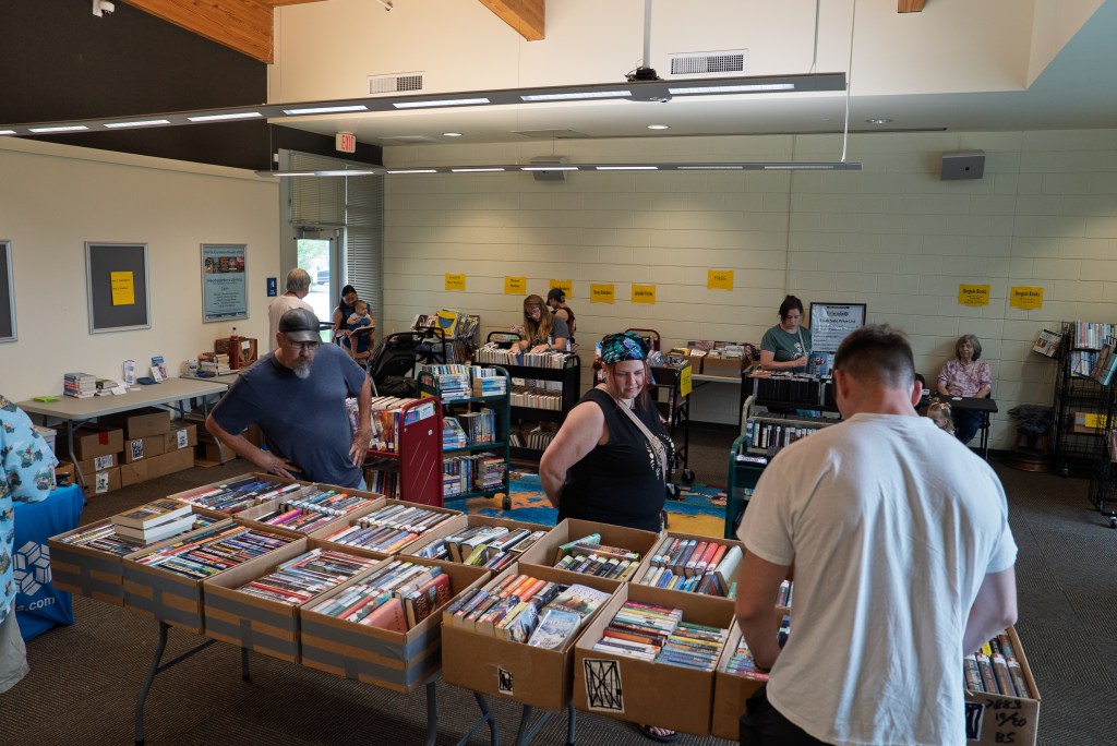 People look through boxes of books on tables in library