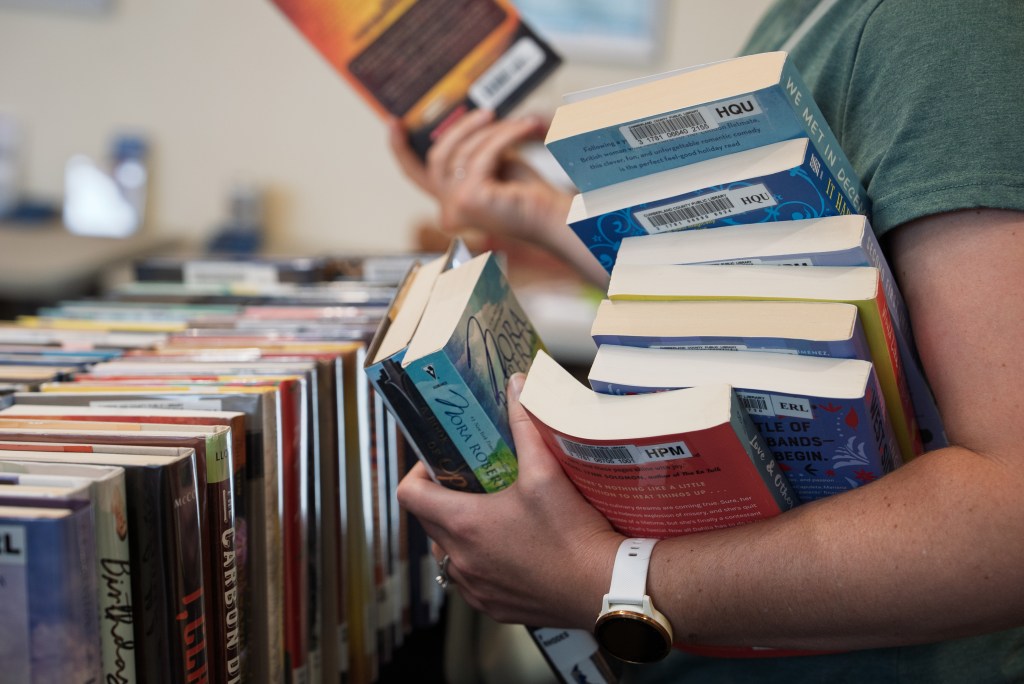 A closeup of a woman's arms holding a pile of books