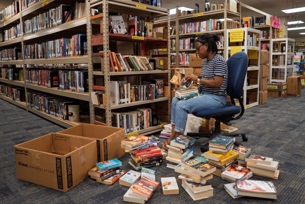 A woman sits in a chair in the library sorting books