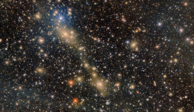 Thousands of stars of different shades of gold and white sparkle in the darkness of space, with a streak of gold going through them
