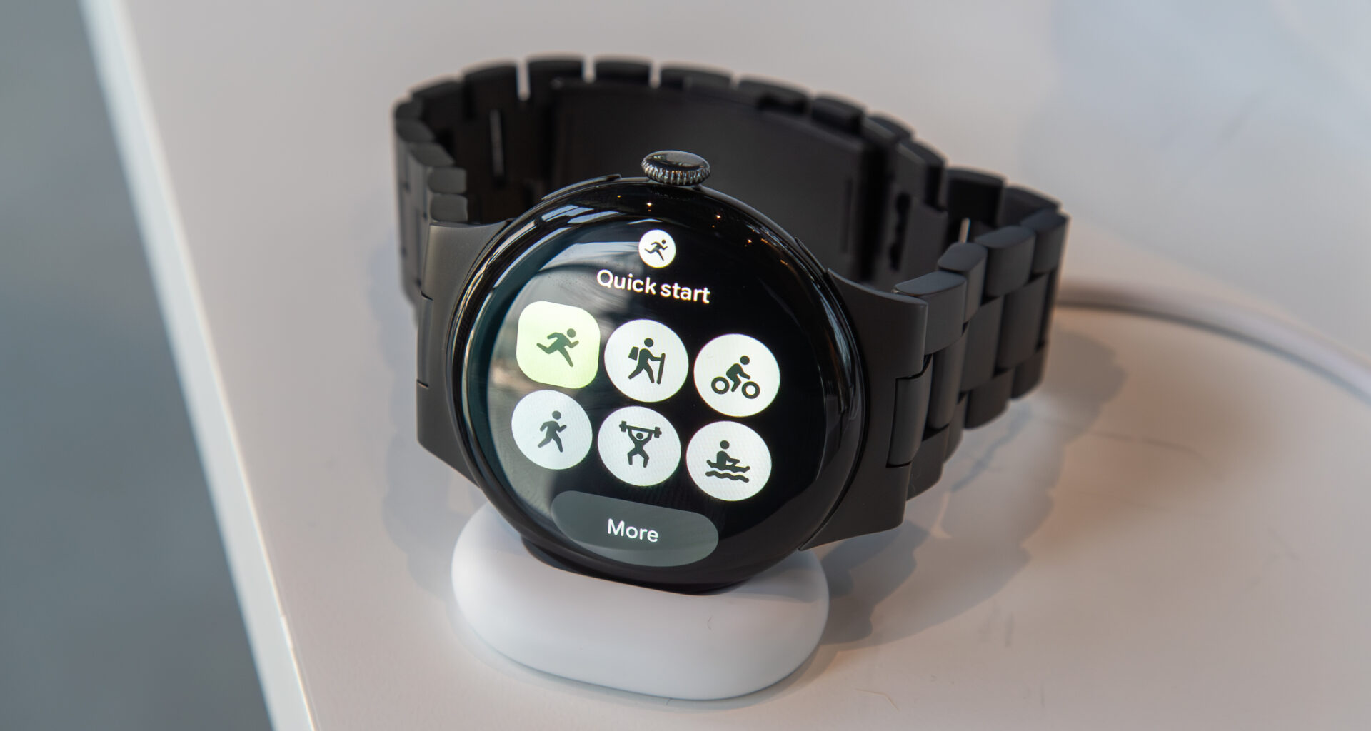 Pixel Watch 4 on the charger showing the Fitbit Quick Start Tile