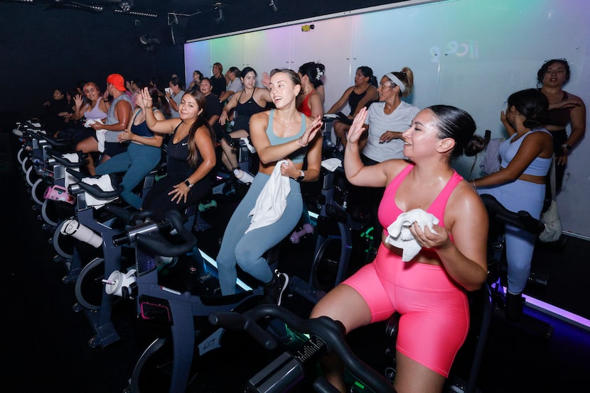 Riders high-fived during an evening cycling class at iiCE Fitness on July 28 in Dallas.