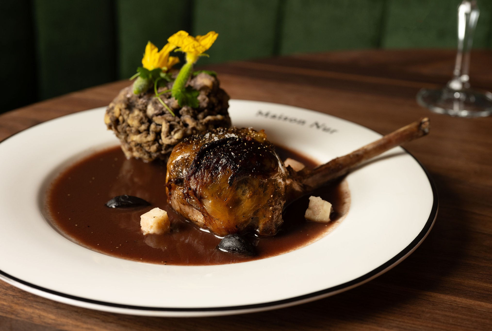 A piece of bone-in meat on a plate with brown broth.