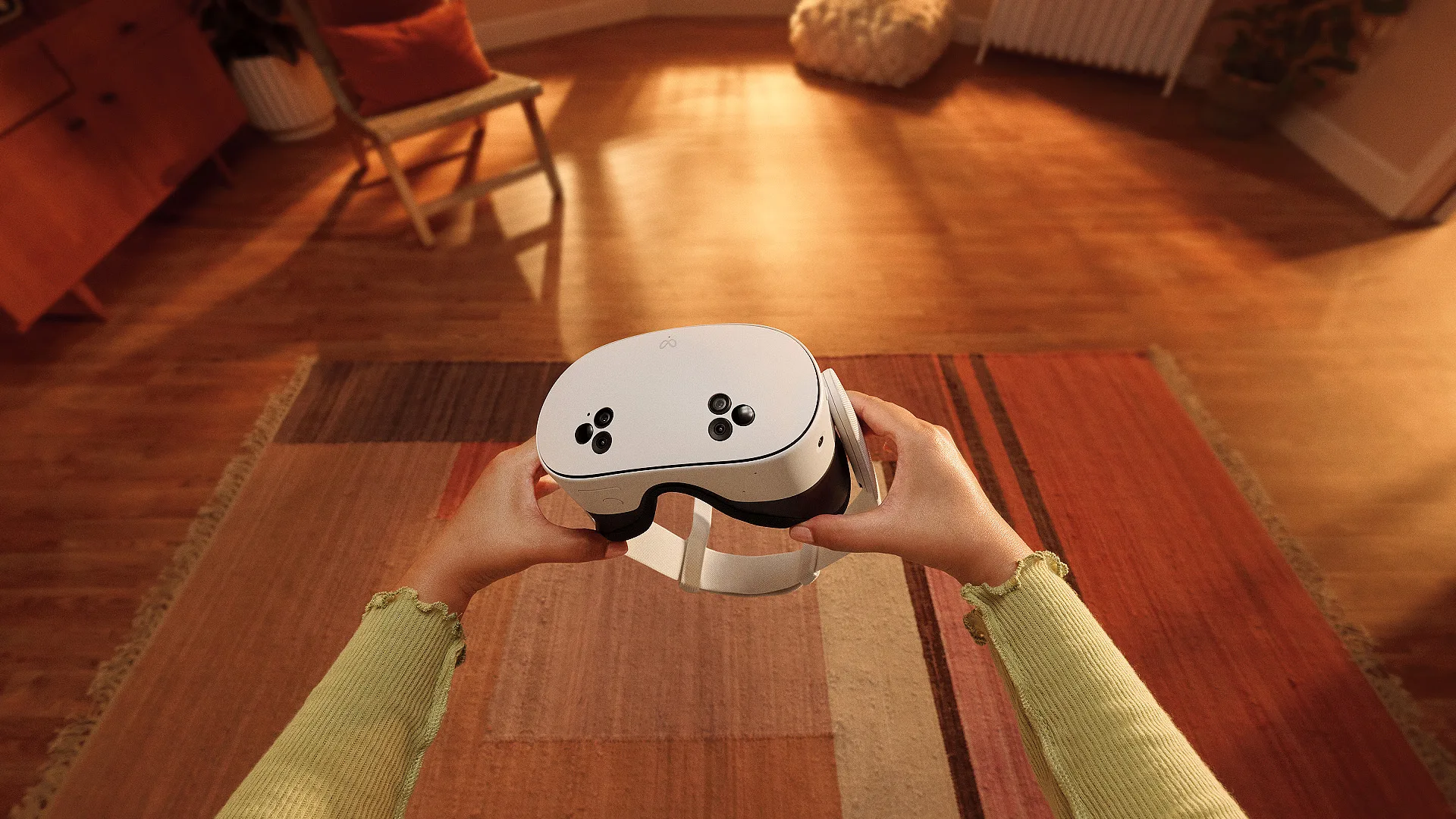Two hands holding a white VR headset in a living room.