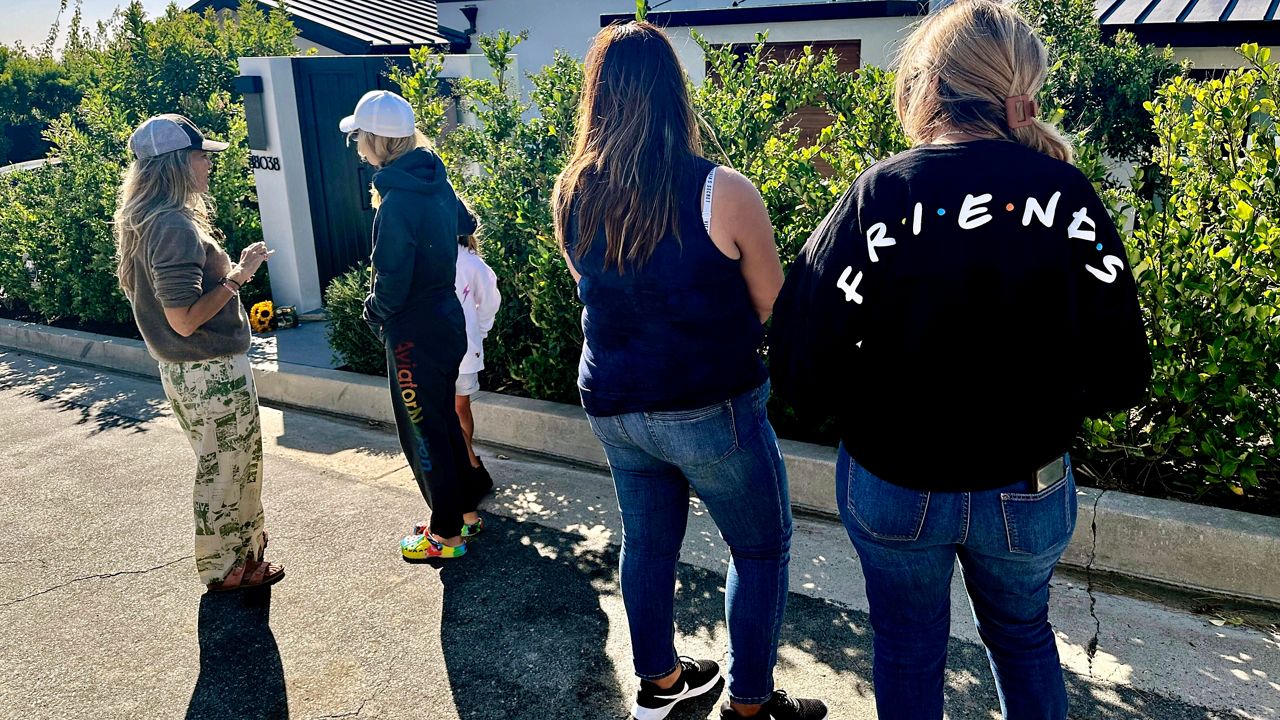 Mourners stand outside the home of actor Matthew Perry, Sunday, Oct. 29, 2023, in the Pacific Palisades area of Los Angeles. Perry, who starred as Chandler Bing in the hit series "Friends," has died. He was 54. (AP Photo/Eugene Garcia)