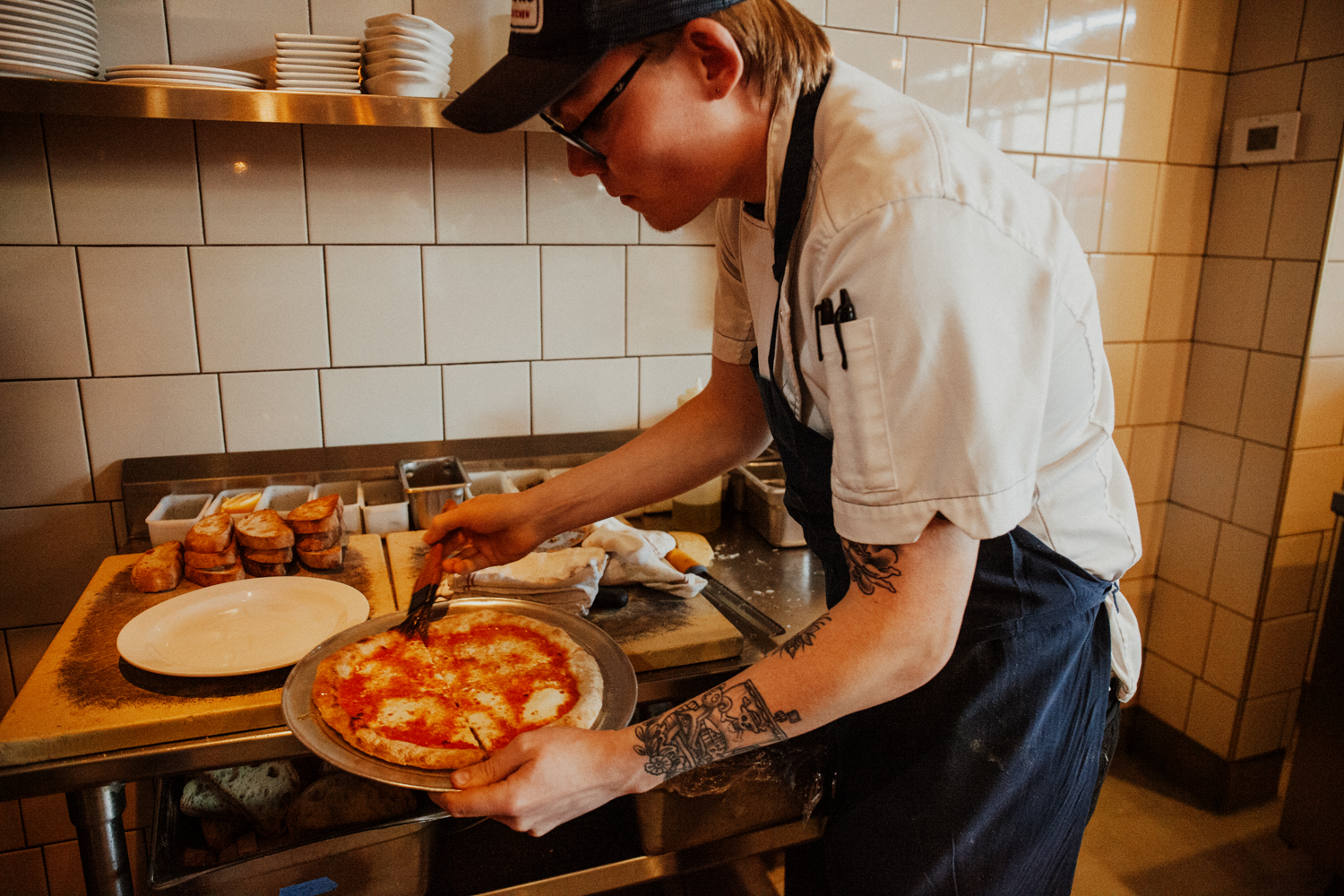 A cook prepping a pizza at Piatello.