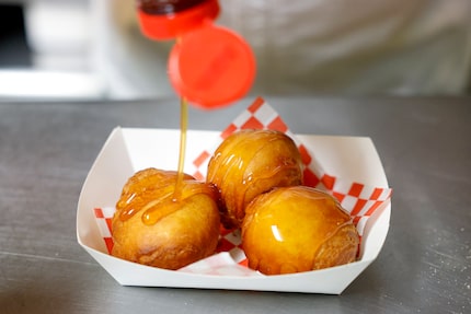 State Fair of Texas concessionaire Abel Gonzales drizzles honey over Fried Butter, the 'most...