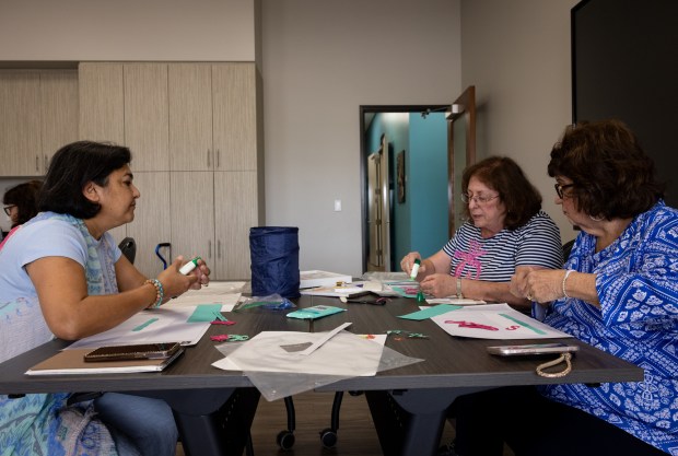 Neena Rahman, left, and Monica Iler are taught how to make a summer themed shadow box during an at class taught by Robin Daus, back right, at San Diego Oasis on Monday, July 14, 2025 in Rancho Bernardo, California. The women talk about having a sense of community at the facility while they laugh and joke. (Ana Ramirez / The San Diego Union-Tribune)