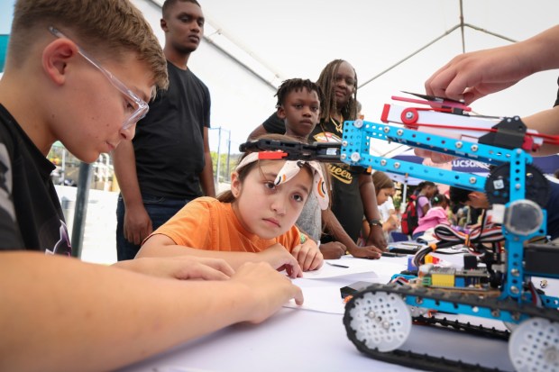 L, Carter Jach, from Robogenesis, shows Violet McGovern a robotic paper airplance launcher during the second annual Southeast San Diego Science & Art Expo at Elementary Institute of Science on Saturday, Aug. 30, 2025 The expo was an inclusive Science fair highlighted science, art, and culture in the world around us including demonstrations in the engineering of lowriders, the science of tortillas, a robotics playground, music, and more. (Sandy Huffaker / For The San Diego Union-Tribune)