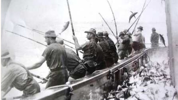 "Fishing from the racks" was a term from the era of tuna clippers specialized fishing vessels equipped with platforms called "racks" that extended along the outside of the stern and port sides, which allowed fishermen to position themselves closer to the water and gain better leverage when lifting fish from the sea. (San Diego Maritime Museum)