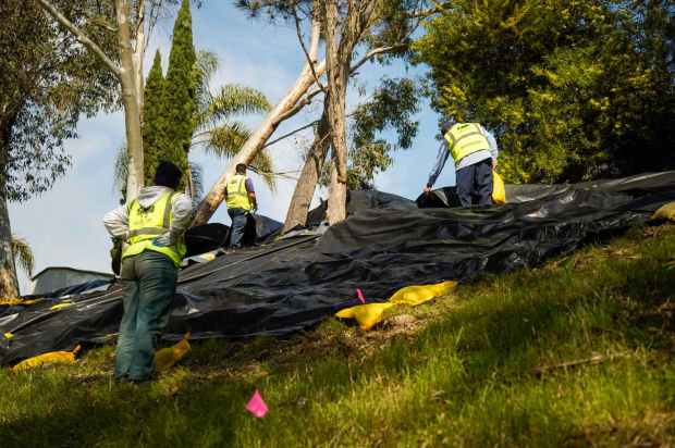 After a hillside behind homes on Trieste Drive in Carlsbad suffered storm-related damage, a crew of Urban Corps of San Diego County worked around the area on Friday, Feb. 16, 2024. (Alejandro Tamayo / The San Diego Union-Tribune)
