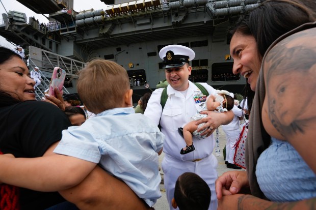 Blayne Benavente hugs and holds his seventh child, baby Luciah, who is one month old and was born while he was deployed onboard the USS Carl Vinson. Benavente was among the sailors on board the USS Carl Vinson returned from deployment to their homeport at Naval Air Station North Island on Thursday, Aug. 14, 2025, in Coronado, CA. (Nelvin C. Cepeda / The San Diego Union-Tribune)