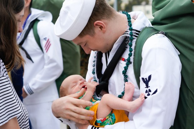 Brianna Sanderson gave the couple's newborn baby to her husband, David Sanderson, to meet his 7-week-old son, Elliot, for the first time. Sailors on board the USS Carl Vinson returned from deployment to their homeport at Naval Air Station North Island on Thursday, Aug. 14, 2025, in Coronado, CA. (Nelvin C. Cepeda / The San Diego Union-Tribune)