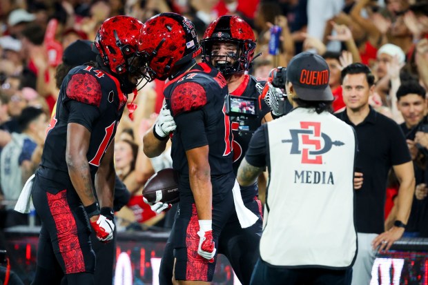 Mikey Welsh #14, Jacob Bostick #17 and Jackson Ford #15 of San Diego State celebrate after a touchdown against Stony Brook during the first half at Snapdragon Stadium on Thursday, Aug. 28, 2025 in San Diego, CA. (Meg McLaughlin / The San Diego Union-Tribune)