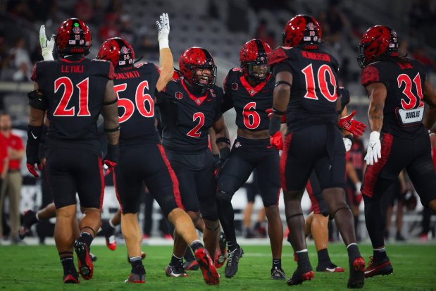 Trey White #2 and Eric Butler #6 of the San Diego State Aztecs, center, celebrate with teammates after a sack against Stony Brook Seawolves during the second half at Snapdragon Stadium on Thursday, Aug. 28, 2025 in San Diego, CA. (Meg McLaughlin / The San Diego Union-Tribune)