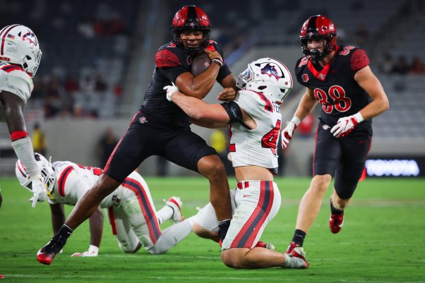 Bert Emanuel Jr. #5 of the San Diego State Aztecs is tackled by Anthony Ferrelli #42 of the Stony Brook Seawolves during the second half at Snapdragon Stadium on Thursday, Aug. 28, 2025 in San Diego, CA. (Meg McLaughlin / The San Diego Union-Tribune)