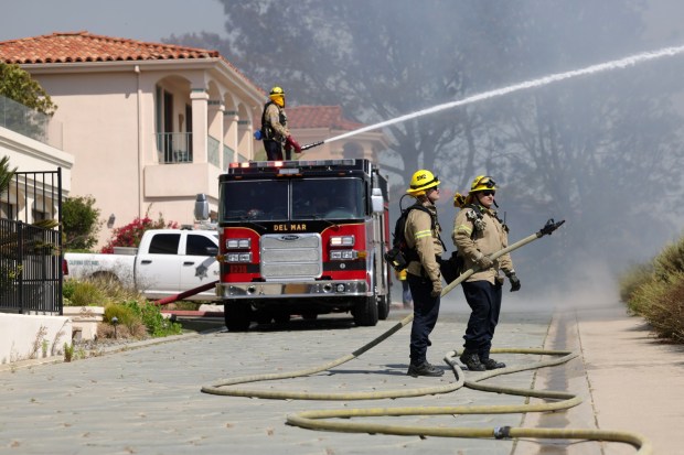 Firefighters work next to homes that were evacuated near the end of Mira Montana as a brushfire burns in the Torrey Pines State Reserve Extension area in San Diego on Tuesday, June 25, 2024. (Hayne Palmour IV / For The San Diego Union-Tribune)