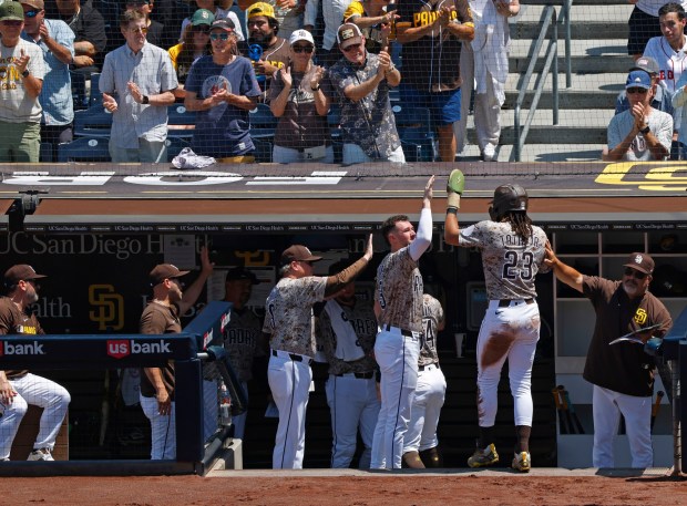 Fernando Tatis Jr. #23 of the San Diego is greeted at the dugout by Jackson Merrill #3 and manager Mike Shildt after scoring on a Luis Arraez two-run double in the third inning against the Boston Red Sox at Petco Park on Aug. 10, 2025 in San Diego, CA. (K.C. Alfred / The San Diego Union-Tribune)