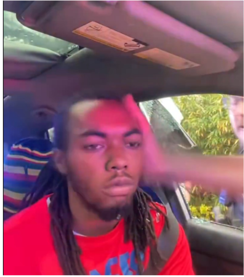 A screen grab showing William McNeil, Jr. being hit by Jacksonville Sheriff's Office Officer D. Bowers. McNeil is wearing a red shirt, and Bowers' hand is seen striking him in the side of the head.