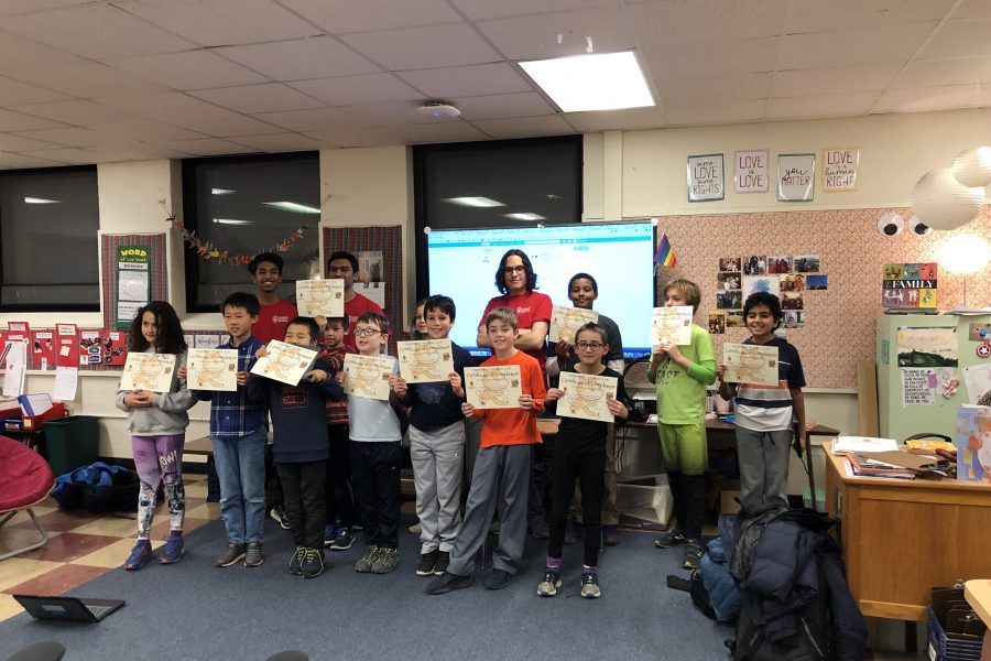 A group of students stand in front of a classroom holding paper certificates. Behind them stand three Computer Science students who have worked with the elementary school students during an after school program.