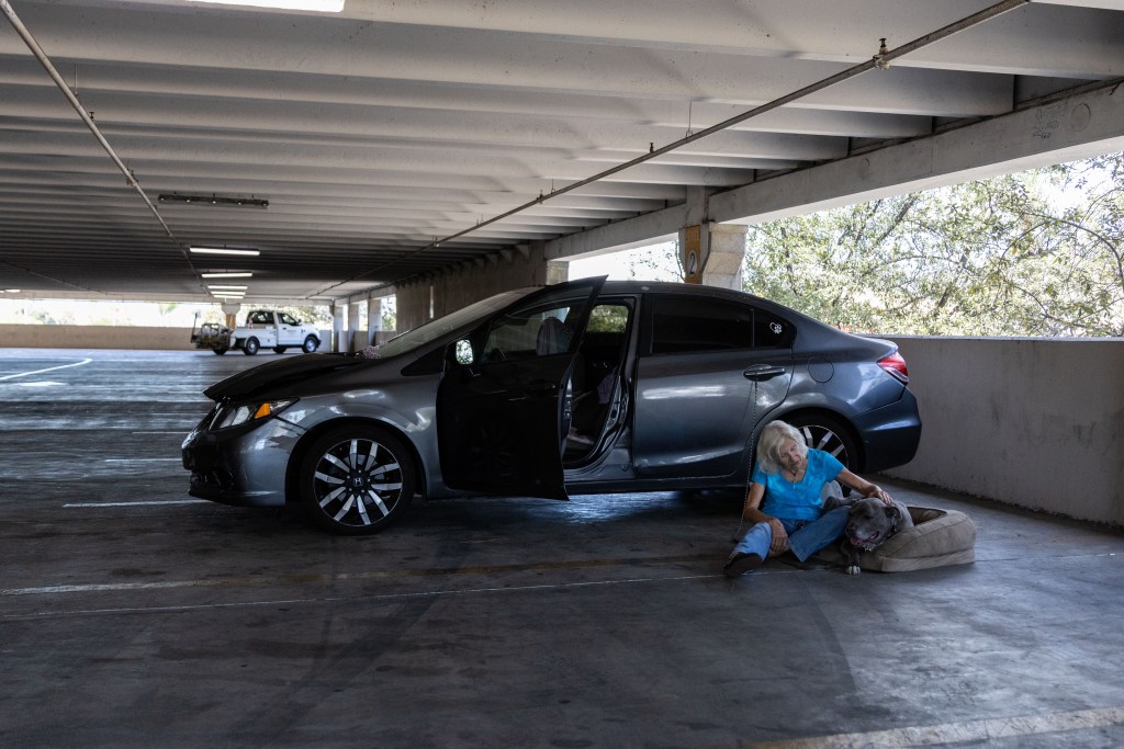 Susan takes Ninja to the parking garage at Parkway Paza in El Cajon to cool him down on Thursday, July 24, 2025. / Brittany Cruz-Fejeran for Voice of San Diego