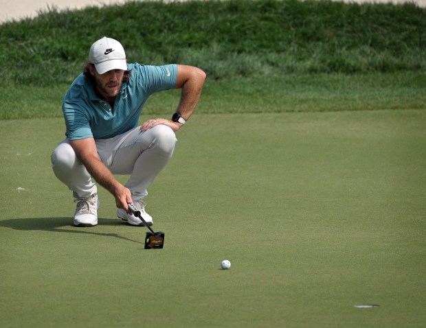 Tommy Fleetwood lines up a putt on the 18th green...