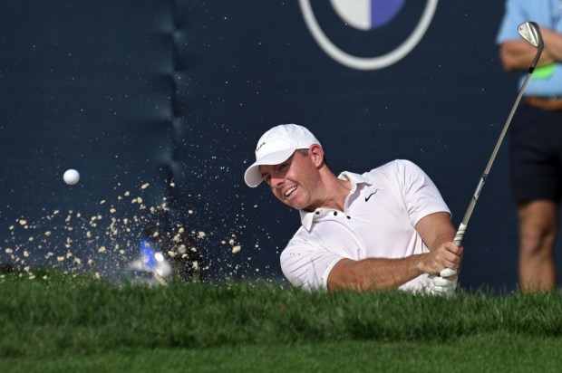 Rory McIlroy hits out of the sand on the 17th...