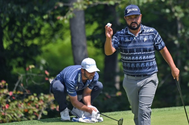 J.J. Spaun raises his ball toward the gallery after sinking...