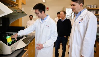 Dr. Bruce Yankner (center) watched as Zhen Kai Ngian (left) described the role of a digital droplet PCR machine used in the team's Alzheimer's research at the lab in the Harvard Medical research building.
