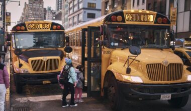 Migrant children take school buses in front of the Row NYC shelter on Tuesday, Dec. 12, 2023. (AP Photo/Andres Kudacki)