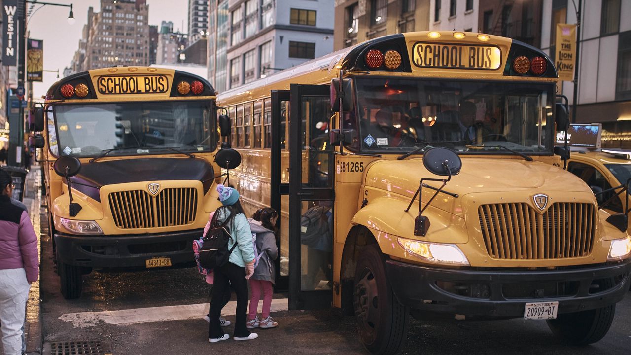 Migrant children take school buses in front of the Row NYC shelter on Tuesday, Dec. 12, 2023. (AP Photo/Andres Kudacki)