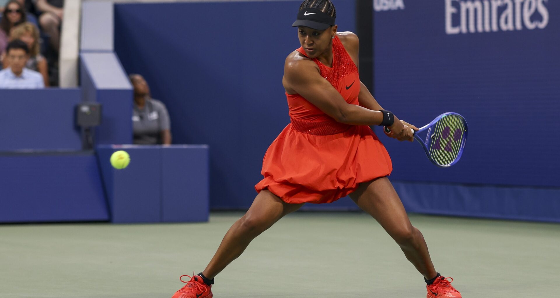 Naomi Osaka playing tennis in a red outfit