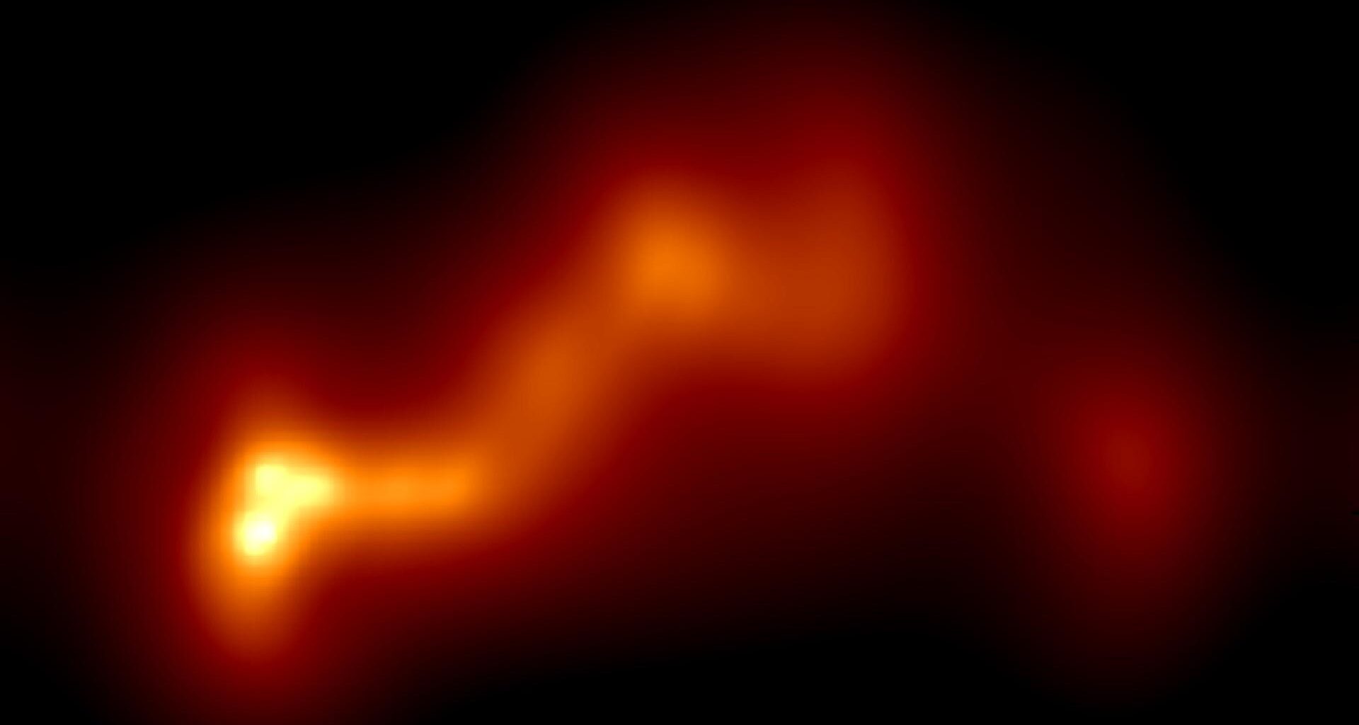 A glowing string of orange and yellow gas in the darkness of space, with a yellow end on the left showing a gas jet of a black hole