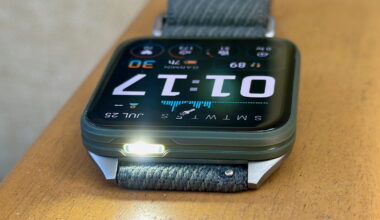A photo of the Garmin Venu X1 sitting on an armrest, display up and facing opposite with the default watch face, the white LED flashlight on and pointing toward the camera.