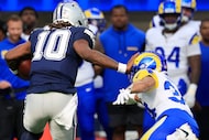 Dallas Cowboys quarterback Joe Milton (10) gives a stiff arm to Los Angeles Rams safety...