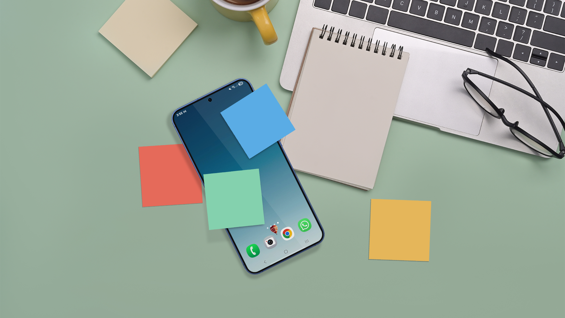 A smartphone with colorful sticky notes placed on its screen lies on a desk, surrounded by a notepad, glasses, a laptop, and a coffee cup.